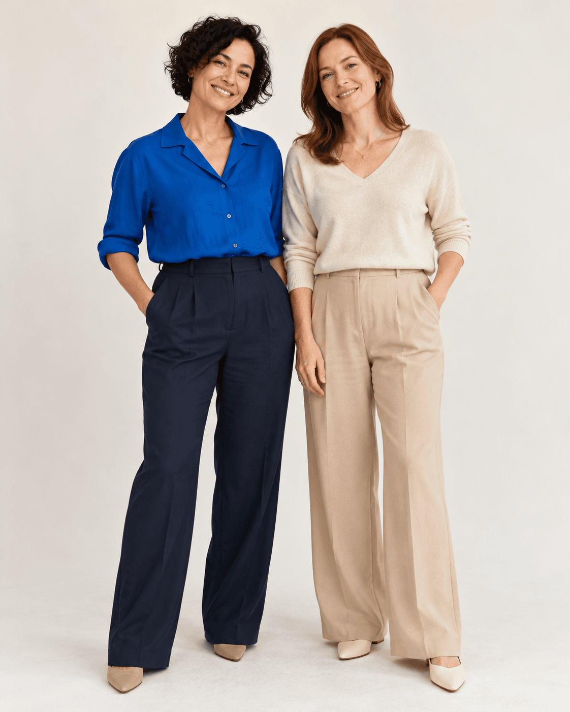 AI-generated concept: two fictional adults against an off-white seamless backdrop, cobalt top with navy trousers and warm neutral outfit, simple side-by-side pose, full-length.