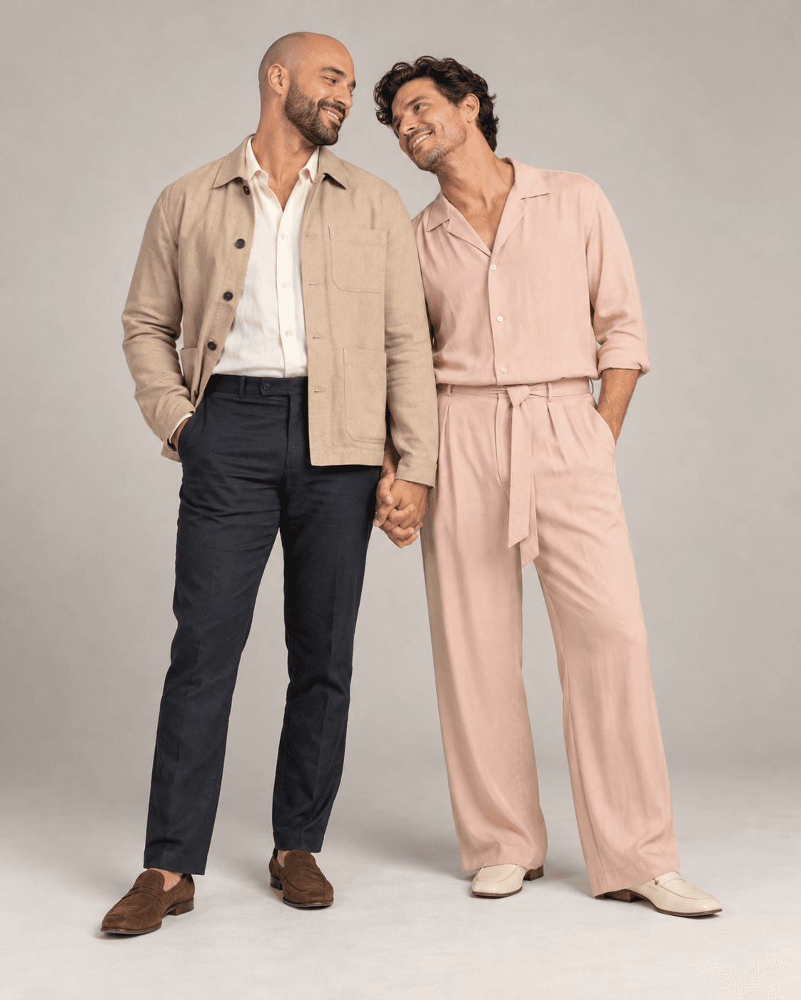 AI-generated full-length studio concept of two fictional adults: Person A wears a sand light jacket and dark trousers; Person B wears plain blush flowing separates.