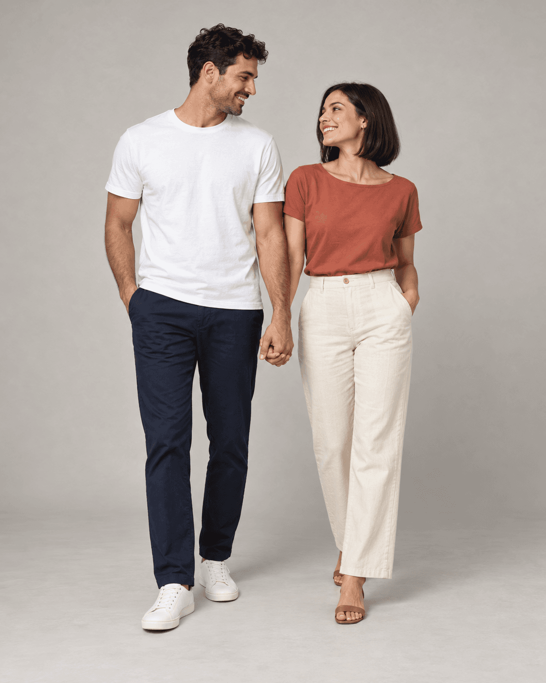 AI-generated full-length studio concept of two fictional adults: Person A wears a white cotton top and navy trousers; Person B wears a terracotta top and cream trousers.